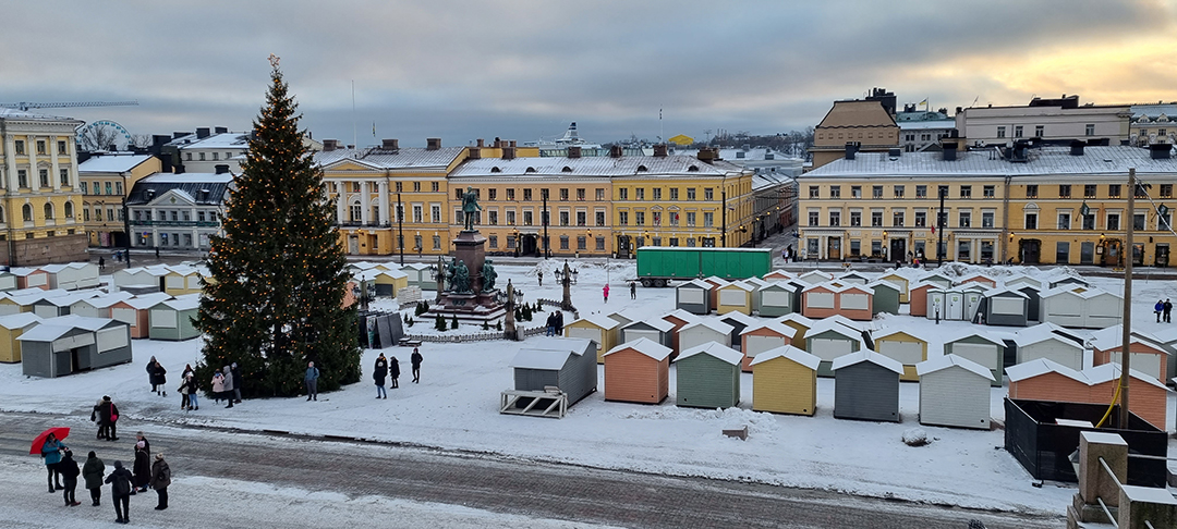 Winter view of Helsinki’s Senate Square with a Christmas tree and colorful market stalls.