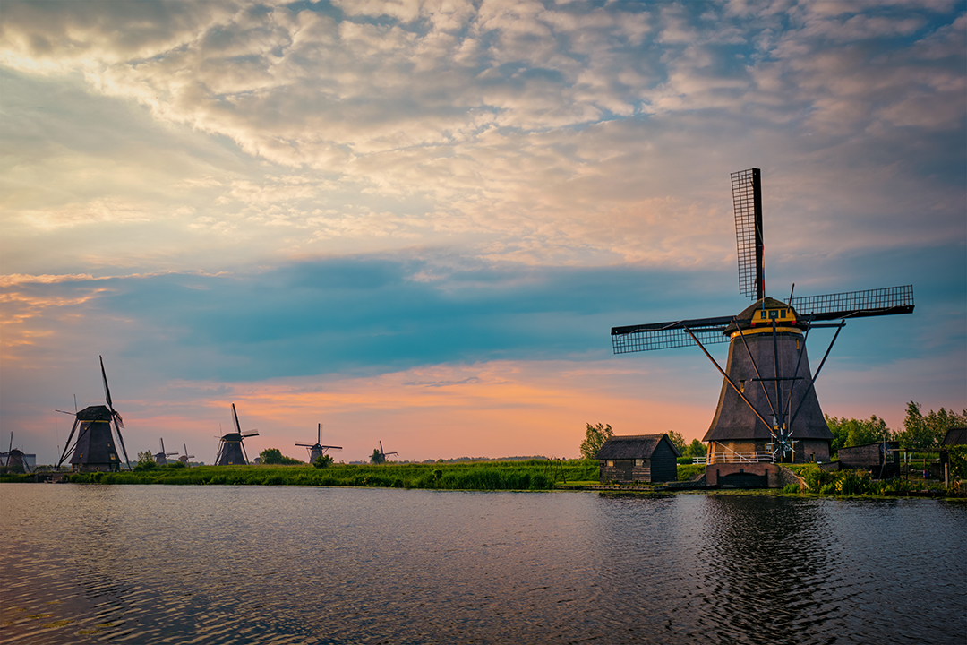 Iconic Dutch windmills reflected in calm waterways, a timeless scene of tradition and landscape harmony.