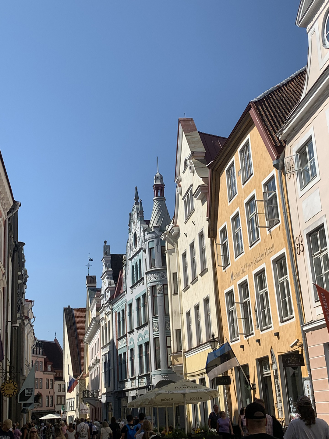 A charming Tallinn Old Town street lined with colorful medieval buildings and a lively summer atmosphere.