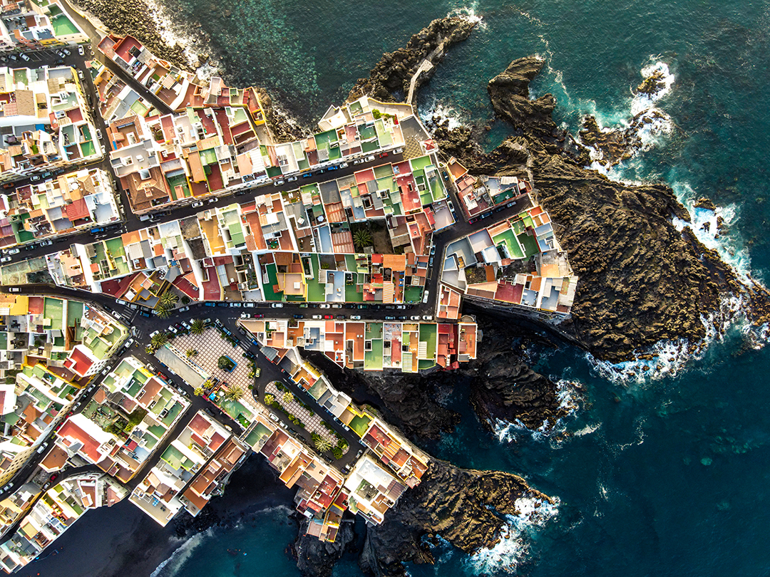 An aerial view of a coastal village in the Canary Islands shows the contrast between settlement and the ocean.