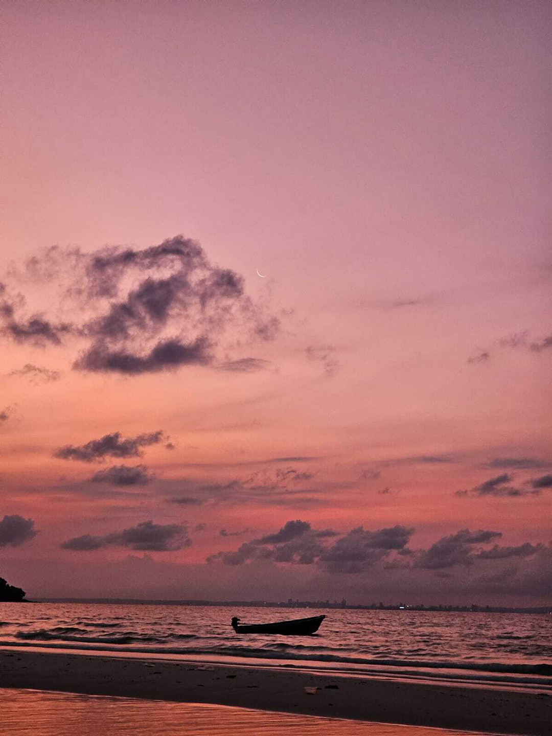 Sunset on Koh Rong Island with calm sea and a small boat creating a relaxed tropical atmosphere.