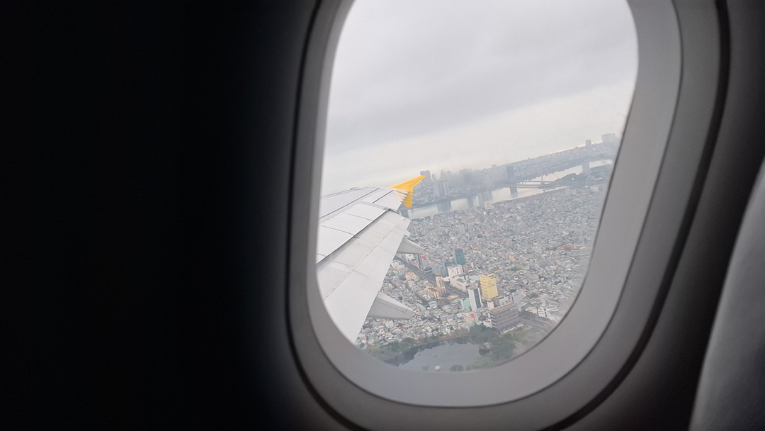 View from an airplane window over Ho Chi Minh City Vietnam during landing, showing dense urban districts, river and city bridges.