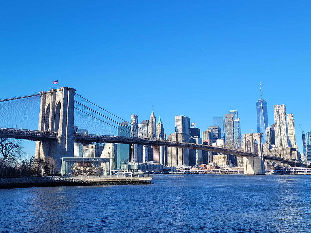 Brooklynski most povezuje Manhattan z Brooklynom, v ozadju pa se dviga sodobna panorama New Yorka z nebotičniki in stolpnico One World Trade Center.