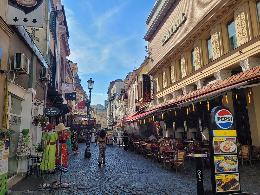 Lively cobbled street with restaurants and cafés in the historic Old Town of Bucharest.