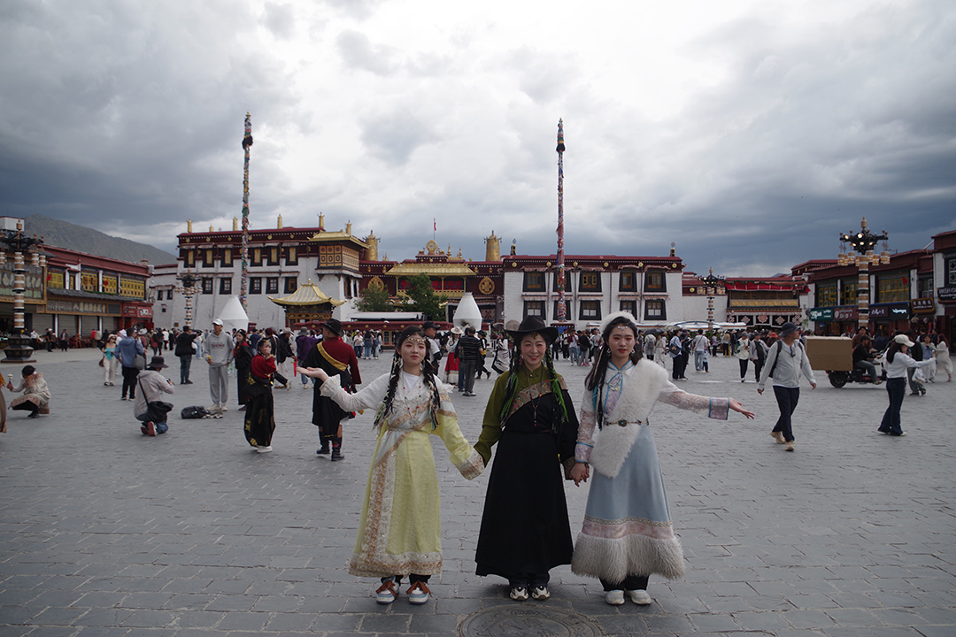Visitors in traditional Tibetan clothing on Barkhor Square in front of Jokhang Temple in the old town of Lhasa.