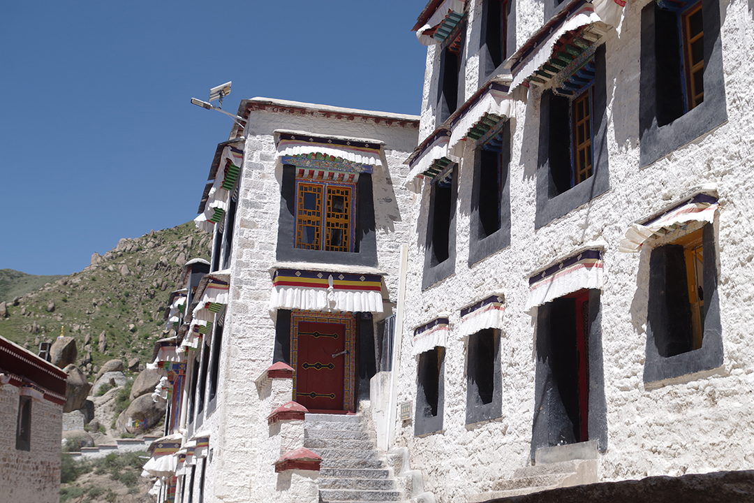 Traditional white monastery buildings at Drepung with distinctive Tibetan windows and colourful architectural details.