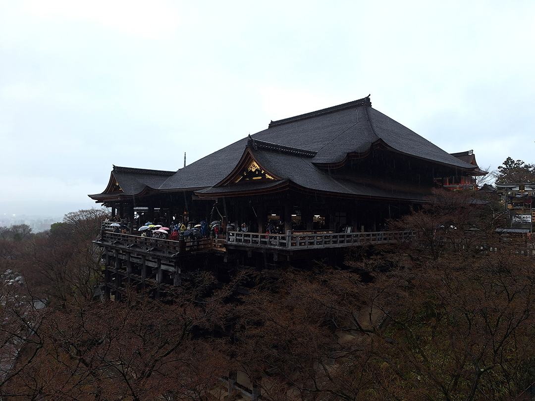 Pogled na tradicionalno leseno stavbo templja Kiyomizu-dera na pobočju nad Kyotom, obdano z drevesi v hladnejšem delu leta.